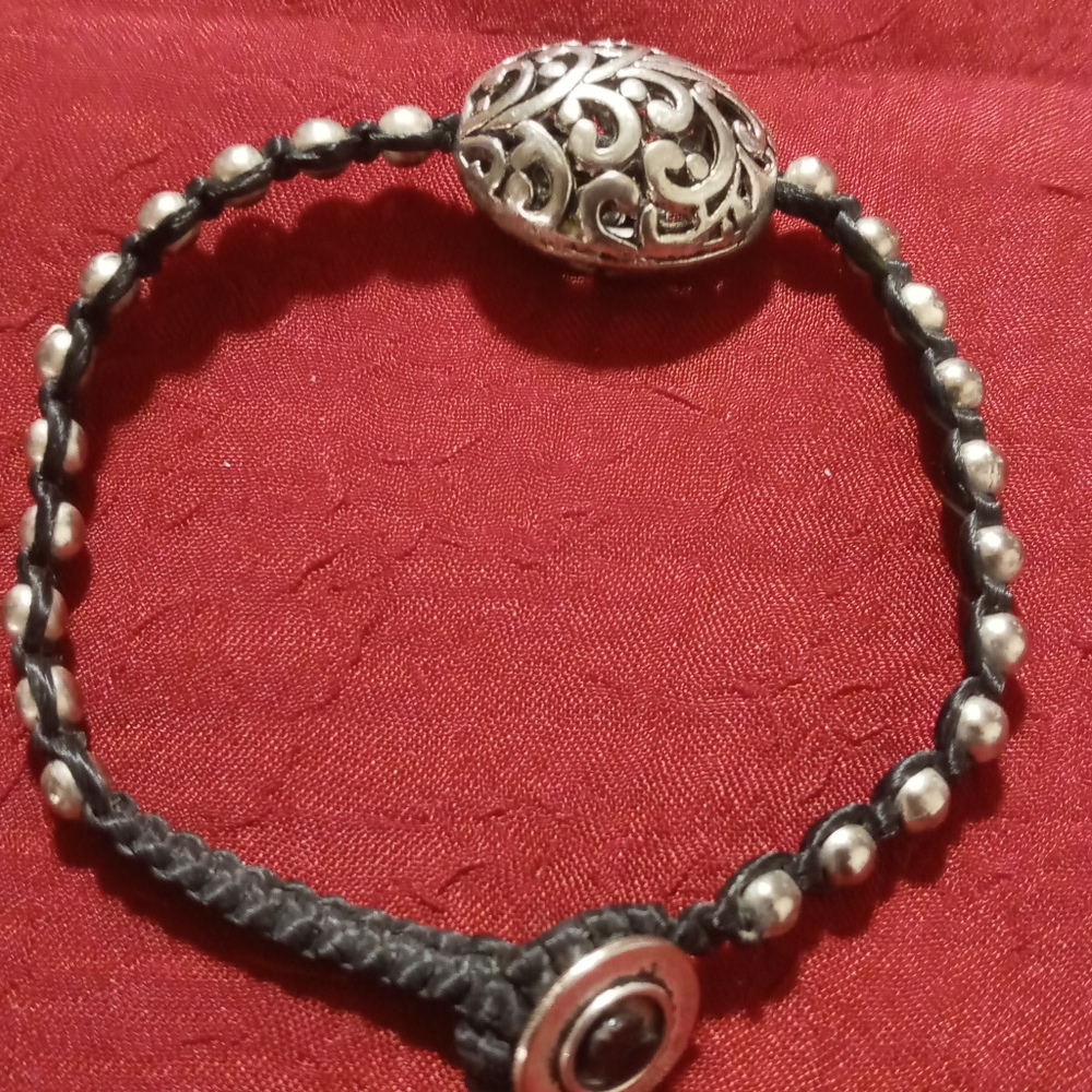 Silver alloy floral fillagre large on wax nylon string bracelet.